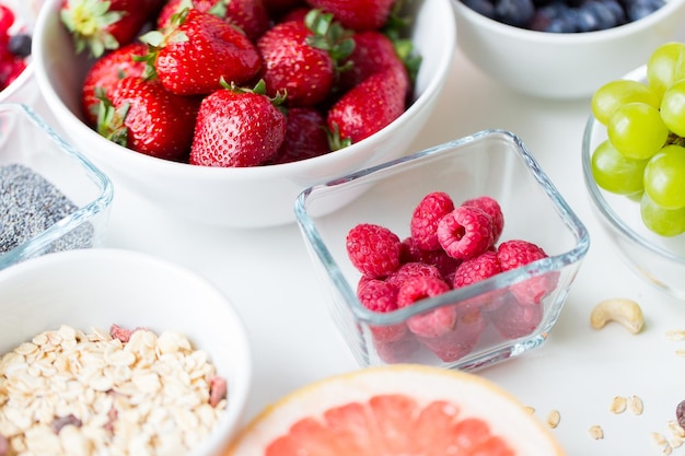 alimentación saludable, dieta, comida vegetariana y concepto de personas: cierre de frutas y bayas en un tazón en la mesa