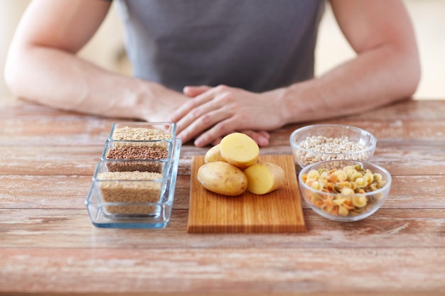 alimentación saludable, dieta y concepto de personas - cierre de manos masculinas con alimentos con carbohidratos en la mesa