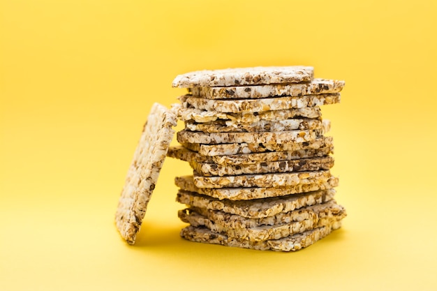 Alimentación saludable. Pan crujiente de avena, trigo, lino y semillas de sésamo en una pila sobre un fondo amarillo. Superalimento