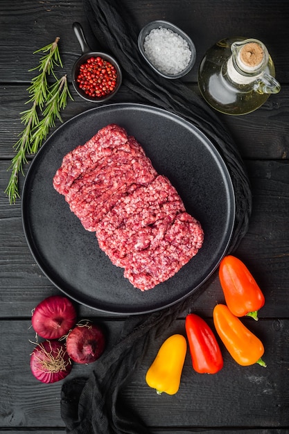 Alimentado de grama orgânica crua, carne moída, no fundo preto da mesa de madeira, vista superior plana lay