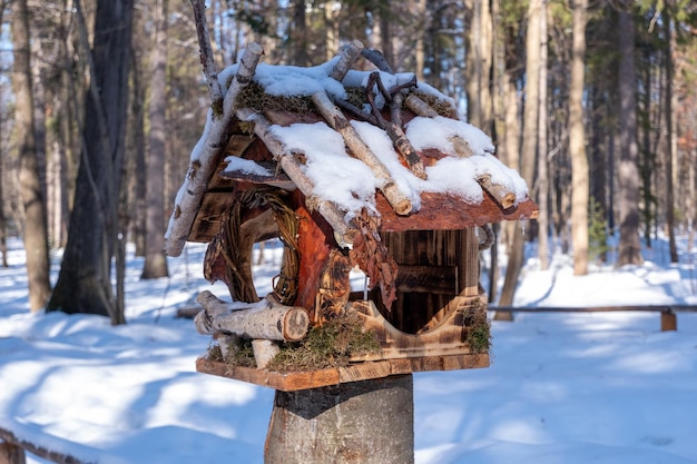 Alimentador de pássaros feito de materiais naturais é colocado em uma floresta de neve de inverno