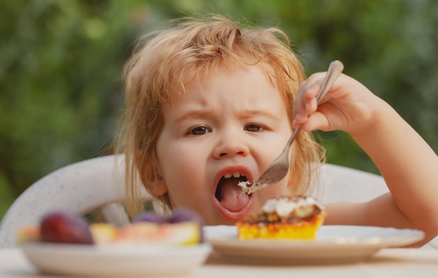 Alimentar a los niños Niño comiendo pastel en el jardín al aire libre en verano Bebé comer