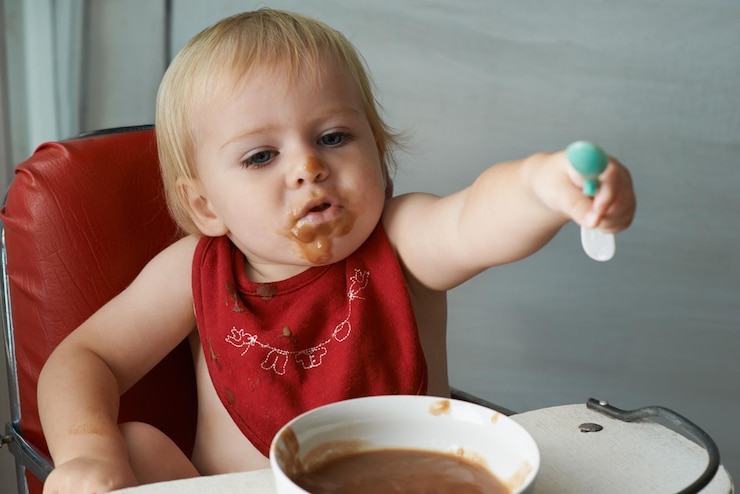 Foto alimentar silla comer y bebé con cuchara en una casa para la alimentación nutrición y diversión mientras juega comida comedor desordenado y niño niño en casa con comida para el desarrollo del niño dieta o nutrición mientras aprende
