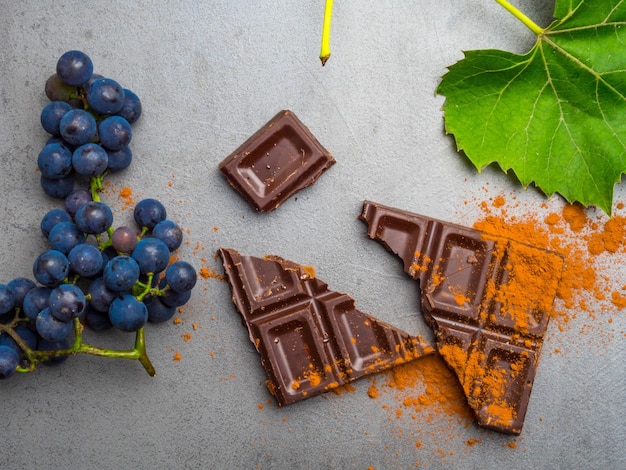 Alimento anticancerígeno bom para sistema cardiovascular uva madura fresca e chocolate amargo em fundo de concreto Alimentos ricos em antioxidantes resveratrol
