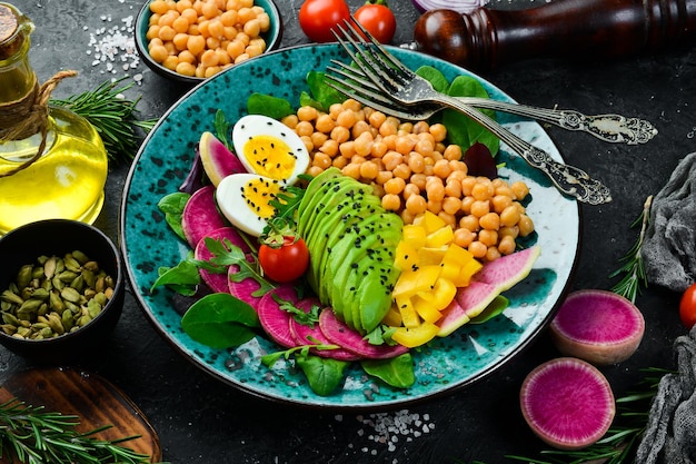 Alimento balanceado: garbanzos, aguacates, huevos, sandía, rábanos y espinacas. Tazón de Buda concepto de comida sabrosa sobre fondo de piedra.