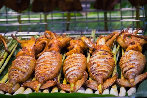 Foto alimento grelhado da rua do calamar em tailândia. lula de churrasco em uma vara muitas das lulas grelhadas.