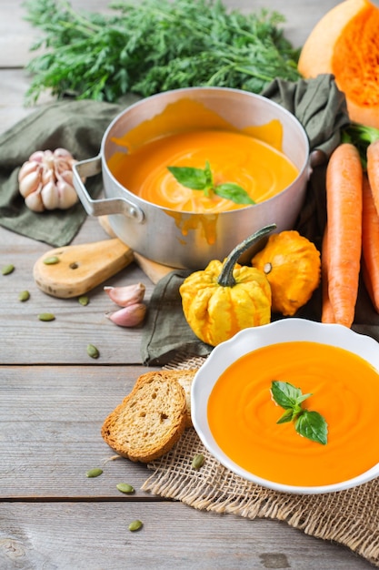 Alimentos y bebidas naturaleza muerta concepto de dieta y nutrición Temporada otoño otoño calabaza naranja asada sopa de zanahoria con ingredientes en una mesa de madera rústica Acogedor fondo de cocina