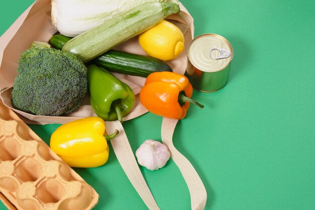 Foto alimentos comestibles en bolsa ecológica de tela en la superficie verde vista superior concepto de estilo de vida sin desperdicio