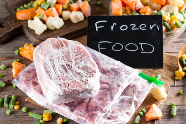 Alimentos congelados. variedade de vegetais congelados e carne na mesa de madeira.