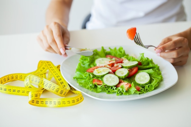 Alimentos dietéticos, primer plano de ensalada fresca en un cuenco y cinta métrica amarilla.