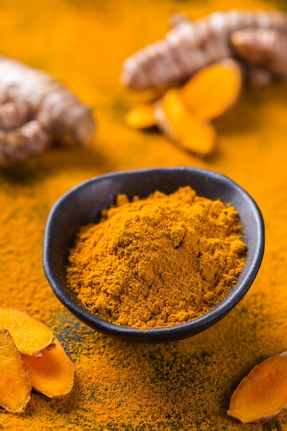 Alimentos e bebidas, nutrição dietética, conceito de cuidados de saúde. Raiz e pó de cúrcuma laranja orgânica crua, curcuma longa em uma mesa de cozinha. Especiarias orientais indianas com baixo teor de colesterol