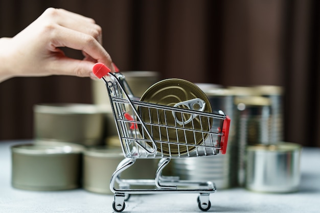 Alimentos enlatados no brinquedo do carrinho de compras com a mão, grupo de alimentos enlatados de alumínio.