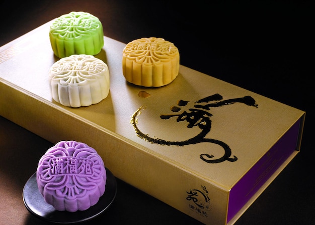 Alimentos de la fiesta china de mediados de otoño Pastel de luna de piel de nieve en mesa de madera con texto verde dorado esmeralda negro loto pasta púrpura yam