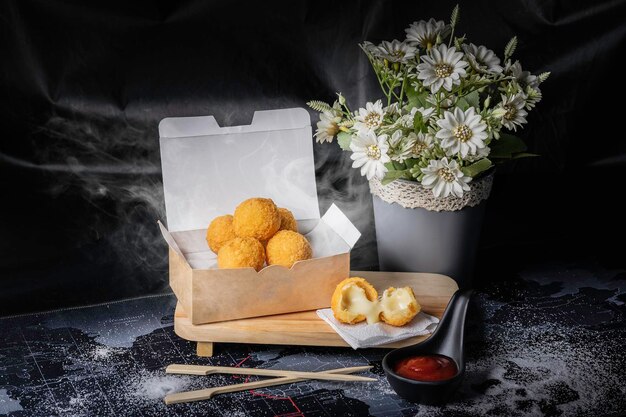 Alimentos fritos redondos amarelos recheados com queijo de fundo preto