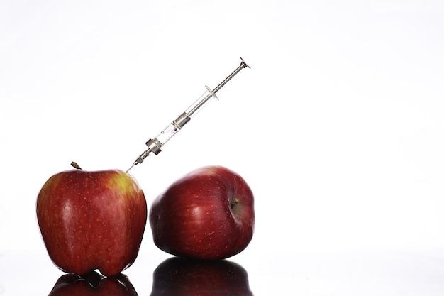 Alimentos geneticamente modificados, maçã bombeada com produtos químicos de uma seringa
