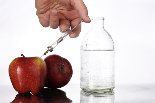 Alimentos genéticamente modificados, manzana bombeada con productos químicos de una jeringa