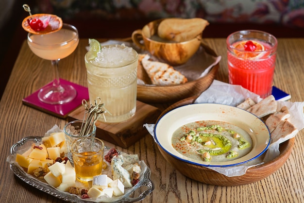 Alimentos hummus geleia diferentes tipos de queijo e coquetéis de álcool na mesa