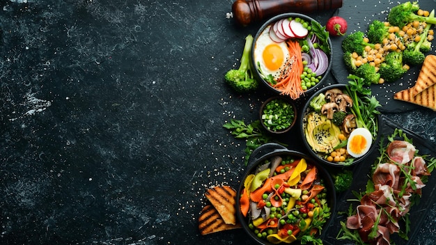 Alimentos massas costelas de porco abacate tigela de Buda e salada de beterraba em um fundo de pedra preta Vista superior Espaço livre para texto