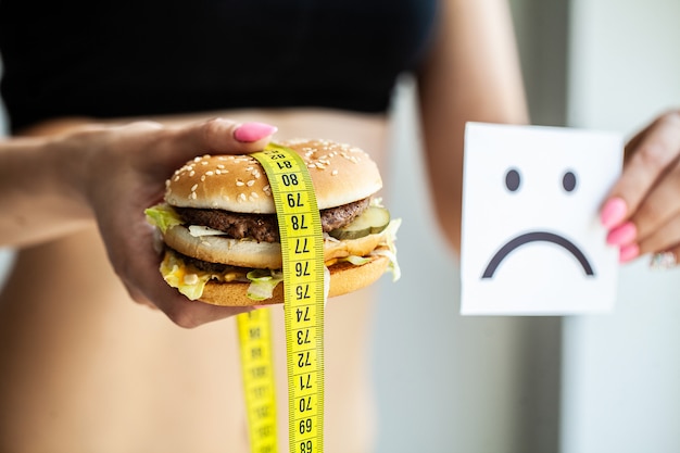 Foto alimentos nocivos, a escolha entre comida maliciosa e esporte, linda garota de dieta,