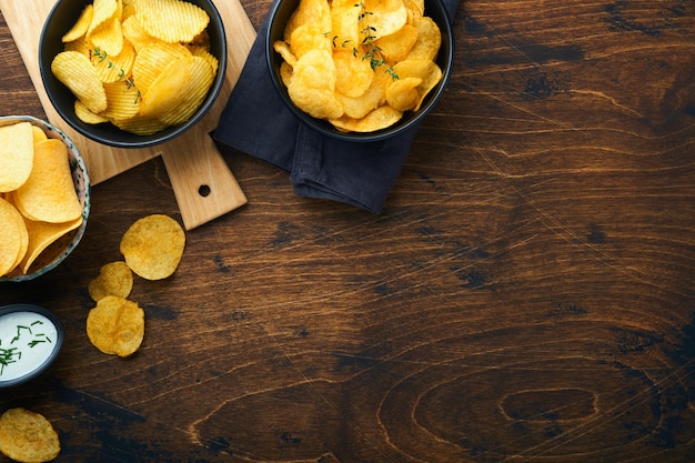 Alimentos o refrigerios poco saludables Todos los refrigerios clásicos de papa con palomitas de maíz y aros de cebolla y pretzels salados en platos de tazón sobre fondo de madera vieja Alimentos poco saludables para los dientes de la piel del corazón de la figura