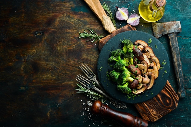 Alimentos orgánicos Champiñones fritos y brócoli en un plato de piedra negra Estilo rústico Vista superior