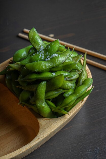 Alimentos orgânicos cozidos em uma tigela de madeira. Edamame tradicional de soja japonesa temperada com sal do mar negro.