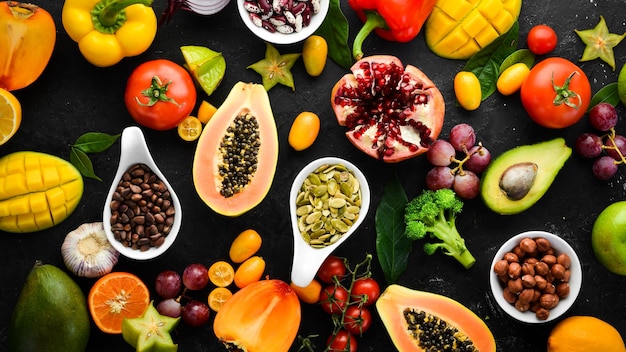 Foto alimentos orgánicos frutas verduras frijoles y nueces sobre un fondo de piedra negra vista superior espacio libre para su texto