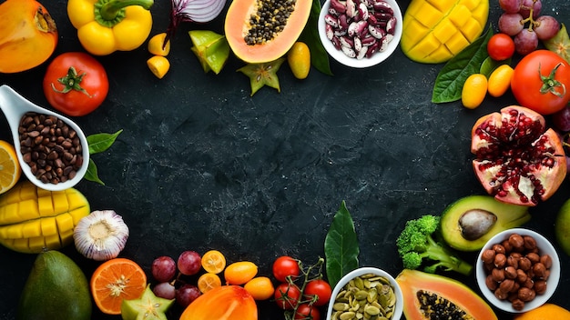 Alimentos orgánicos Frutas verduras frijoles y nueces sobre un fondo de piedra negra Vista superior Espacio libre para su texto