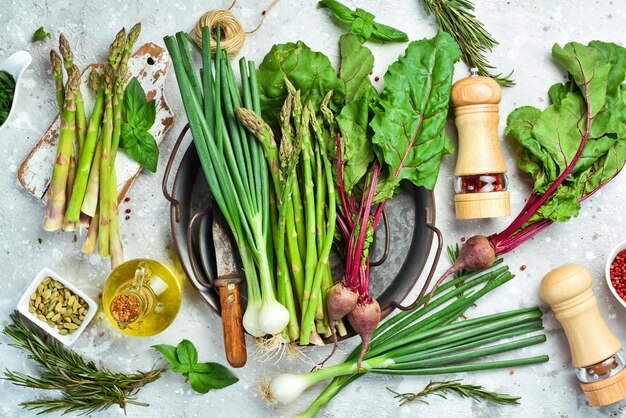 Alimentos orgánicos saludables Espárragos frescos, cebollas verdes y remolacha roja en una mesa de cocina de piedra Verduras Estilo rústico