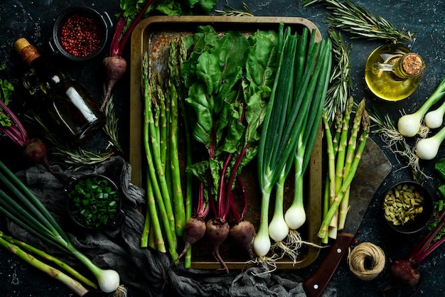 Alimentos orgánicos saludables Espárragos frescos, cebollas verdes y remolacha roja en una mesa de cocina de piedra Verduras Estilo rústico