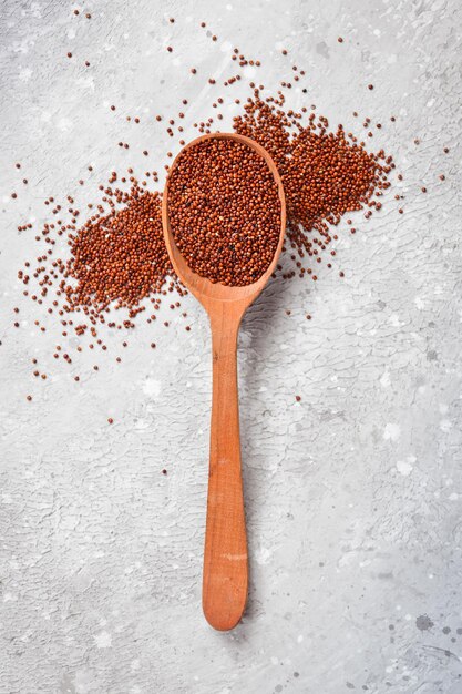 Alimentos Orgânicos Saudáveis. Seque a quinoa marrom em uma colher de pau. Em um fundo de pedra cinza. Vista do topo.