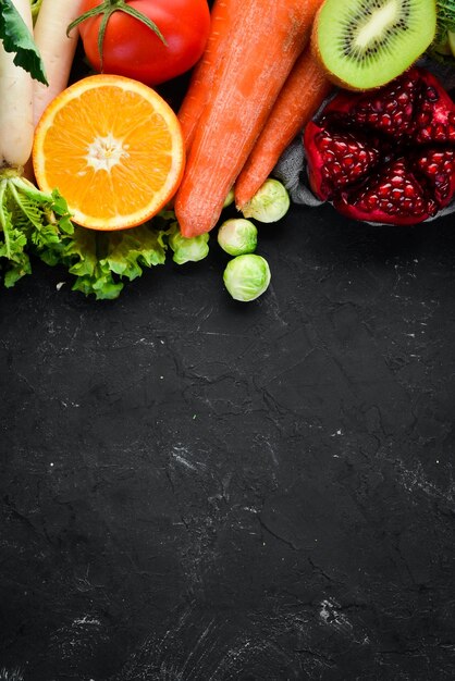 Alimentos orgánicos sobre un fondo de piedra negra Verduras y frutas Vista superior Espacio de copia libre