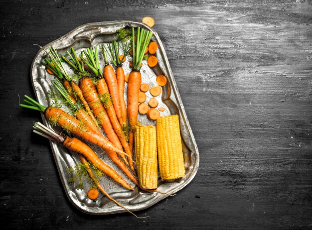 Alimentos orgánicos Zanahorias frescas en una bandeja de acero en la pizarra negra