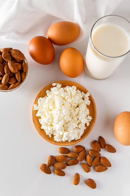 Alimentos proteicos sobre un fondo blanco requesón huevos nueces Un conjunto de alimentos saludables para una dieta equilibrada