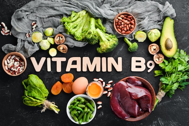 Alimentos que contêm vitamina natural b9 fígado abacate brócolis espinafre feijão salsa nozes em um fundo de pedra preta vista superior