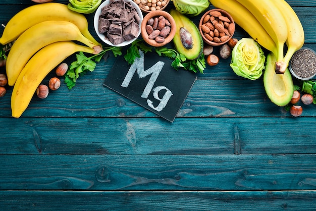 Alimentos que contienen magnesio natural Mg Chocolate plátano cacao nueces aguacates brócoli almendras Vista superior Sobre un fondo de madera azul