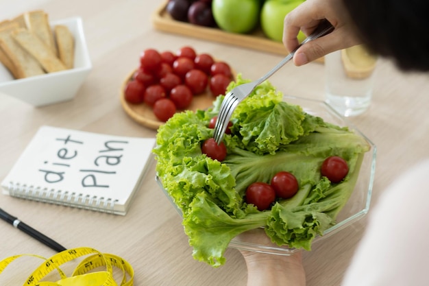 Alimentos saludables Las mujeres planean hacer dieta para una forma delgada y saludable Mujer comiendo ensalada de verduras y tomates