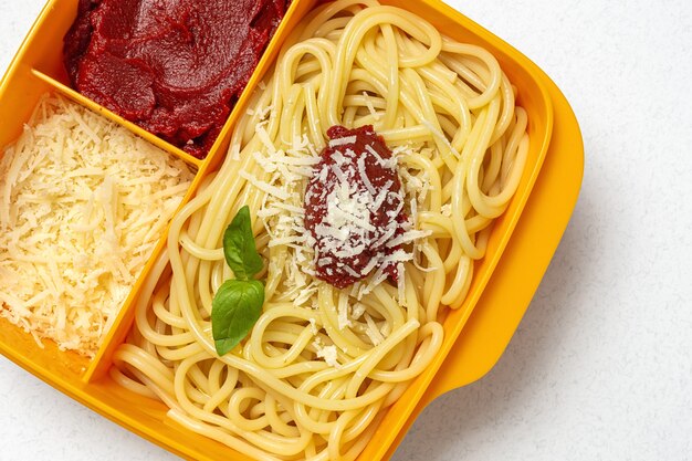 Alimentos saudáveis em recipientes plásticos prontos para comer com espaguete caseiro com tomate, queijo e manjericão na mesa de trabalho. comida italiana. para tirar.