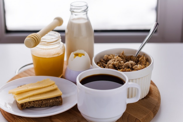 Foto alimentos saudáveis para o café da manhã, leite, mel, cereais, café, ovos cozidos, café, sanduíche com queijo