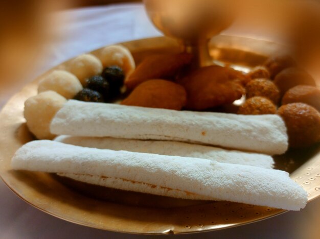 Foto los alimentos tradicionales de assam como el pitha laddu doi sira con el fondo de la gamosa assamesa