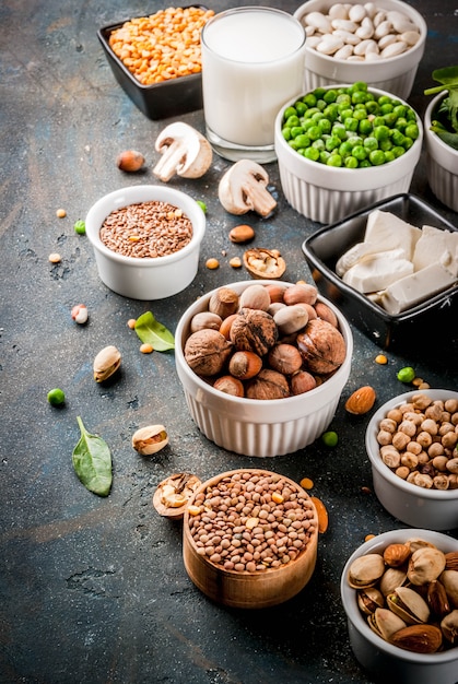 Alimentos veganos de dieta saudável, fontes de proteínas vegetarianas: Tofu, leite vegano, feijão, lentilha, nozes, leite de soja, espinafre e sementes. Vista superior na mesa branca.