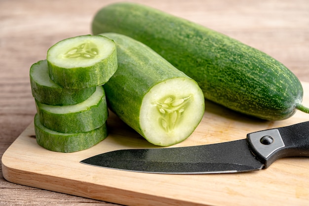 Alimentos vegetais de pepino cortados em fatias e faca na tábua para cozinhar na cozinha.