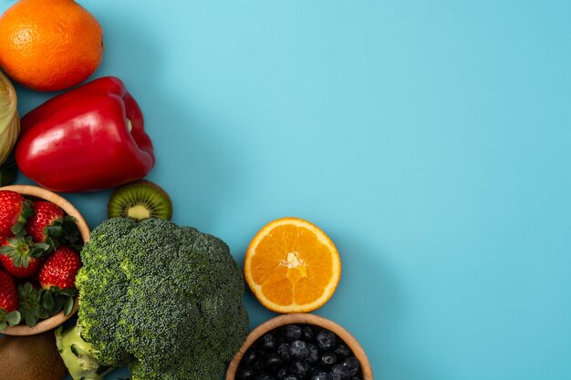 Alimentos vegetales saludables sobre fondo azul.