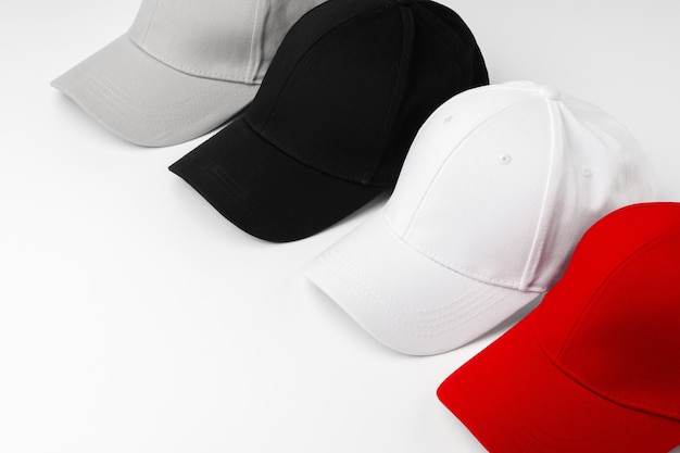 Alineación de cuatro gorras de béisbol en blanco rojo y negro sobre un fondo blanco