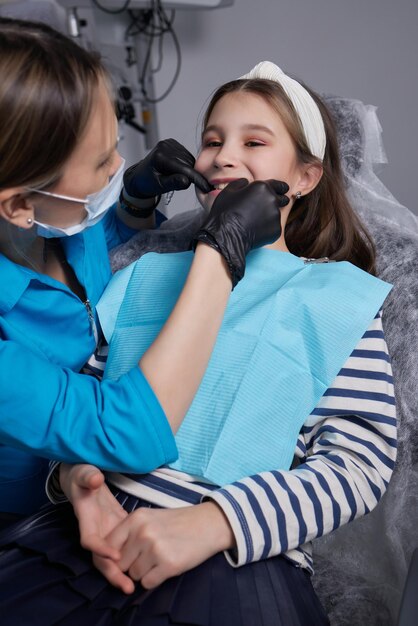 Alineador invisible de niña caucásica y apuntando a sus dientes rectos perfectos. Concepto de confianza y salud dental.