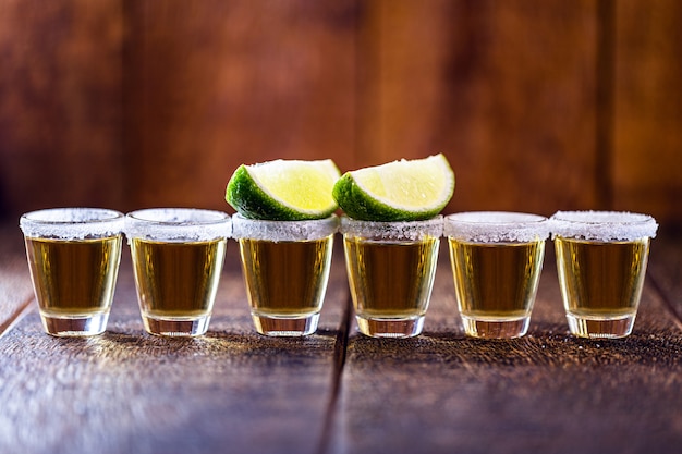 Foto se alinearon varios vasos de tequila, bebida de la cultura mexicana, hecha de alcohol destilado, limón, sal y agave azul. día internacional del tequila. copiar para texto.