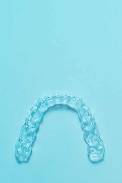 Alinhadores de dentes de colchetes dentais invisíveis em fundo turquesa. Aparelhos plásticos, retentores odontológicos para endireitar os dentes.
