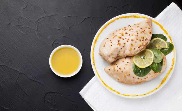 Aliste el pollo al lado de las salsas y la mostaza en un fondo negro.