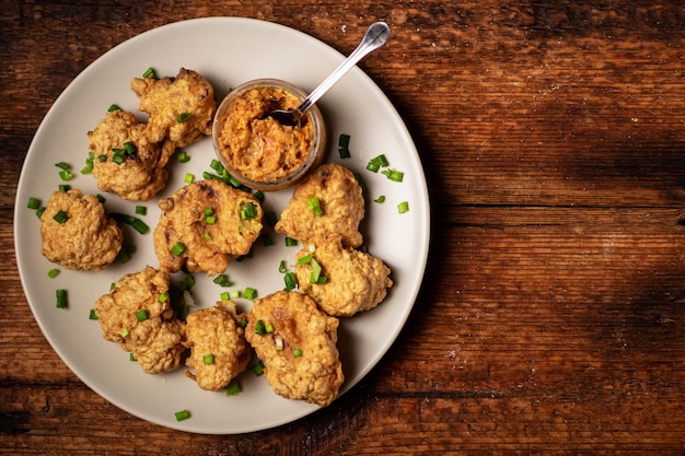 Alitas de coliflor comida Trozos de coliflor cocidos rebozados en un plato sobre un fondo de madera Lugar para el texto