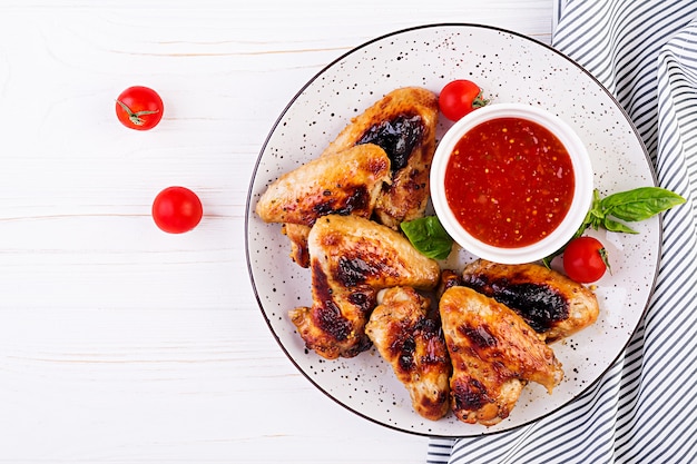 Alitas de pollo al horno al estilo asiático y salsa de tomate en un plato, vista superior